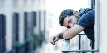 Nachdenklicher Mann mit Zigarette auf dem Balkon