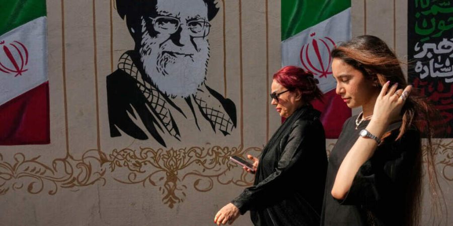 ARCHIV - Frauen gehen in der Innenstadt an einem Porträt des verstorbenen iranischen Obersten Führers Ayatollah Ali Chamenei, der bei einem Angriff der USA und Israels am 28. Februar ...