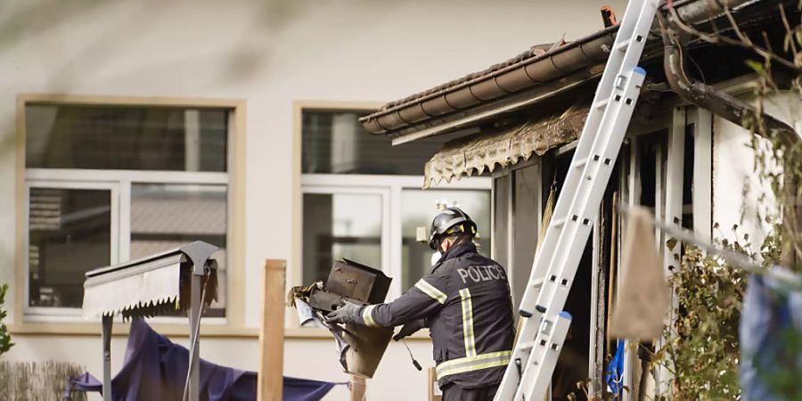 Ein Berner Kantonspolizist am Montag bei Aufräumarbeiten im vom Brand zerstörten Wohnhaus.