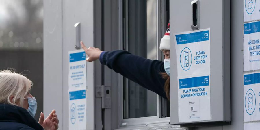 Ein Mitarbeiter eines Corona-Testzentrums weist einer Frau den Weg. Die neue Coronavirus-Variante Omikron ist in weiteren europäischen Ländern aufgetaucht. Foto: Joe Giddens/PA Wire/dpa