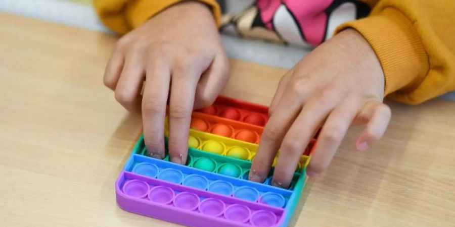 In einem Klassenzimmer einer Bielefelder Grundschule spielt ein Kind mit Pop-Its. Foto: Guido Kirchner/dpa