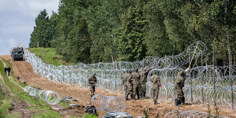 ARCHIV - Polnische Soldaten errichten einen Stacheldrahtzaun entlang der polnisch-belarussischen Grenze. Nach Einschätzung von Menschenrechtlern verschärft sich die Lage für Migranten auf dem Weg Richtung EU immer mehr. Das teilte die belarussische Menschenrechtsorganisation Human Constanta mit. Foto: Attila Husejnow/SOPA Images via ZUMA Press Wire/dpa