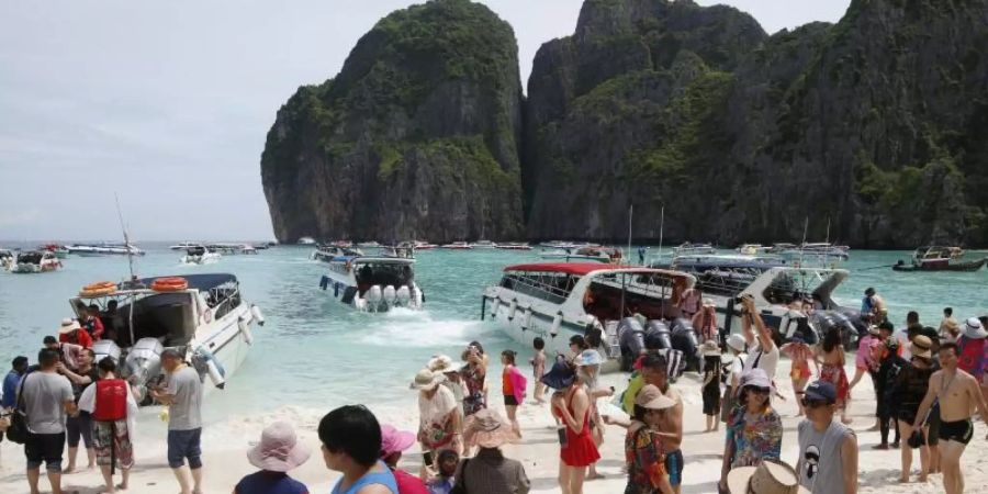 Touristen besuchen den Strand Maya Bay. Foto: Sakchai Lalit/AP/dpa