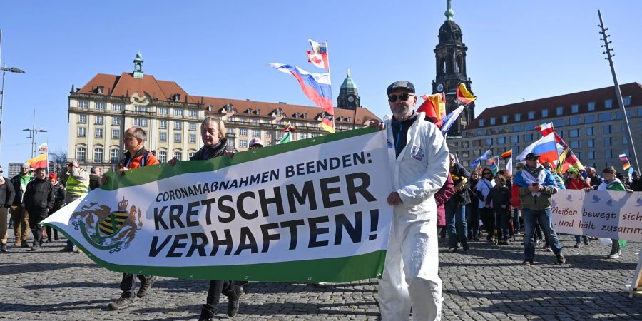 «Coronamassnahmen beenden: Kretschmer verhaften!» fordern etwa diese Teilnehmer. Im Hintergrund sind mehrere Russland-Fahnen zu erkennen.