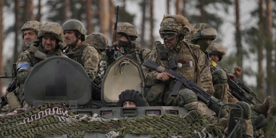 Ukrainische Soldaten sitzen auf einem Schützenpanzer, während sie von russischen Soldaten aufgegebene Stellungen nahe Kiew durchfahren.