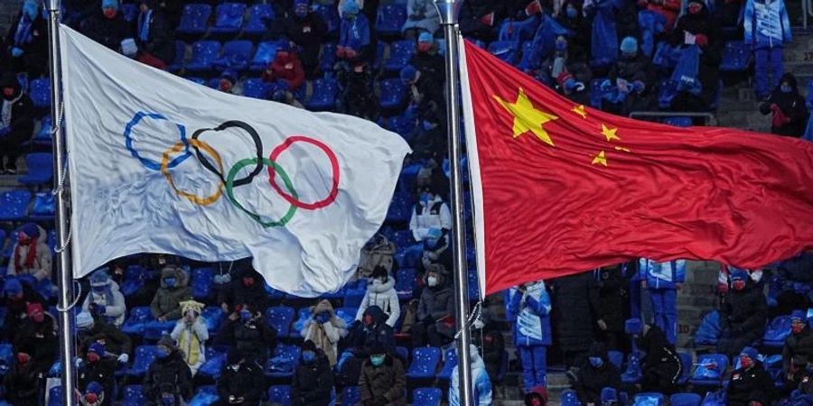 Die Olympische und die chinesische Flagge wehen nebeneinander bei der Eröffnungsfeier der Winterspiele in Peking. Foto: Michael Kappeler/dpa