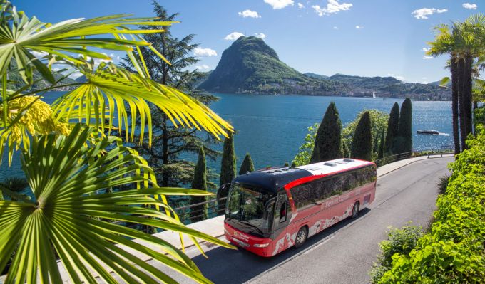 Von Tirano nach Lugano geht es nicht auf Schienen. Der Bernina Express Bus bringt seine Fahrgäste auf der Strasse ans Ziel. See Palmen Sonne Buss Berge