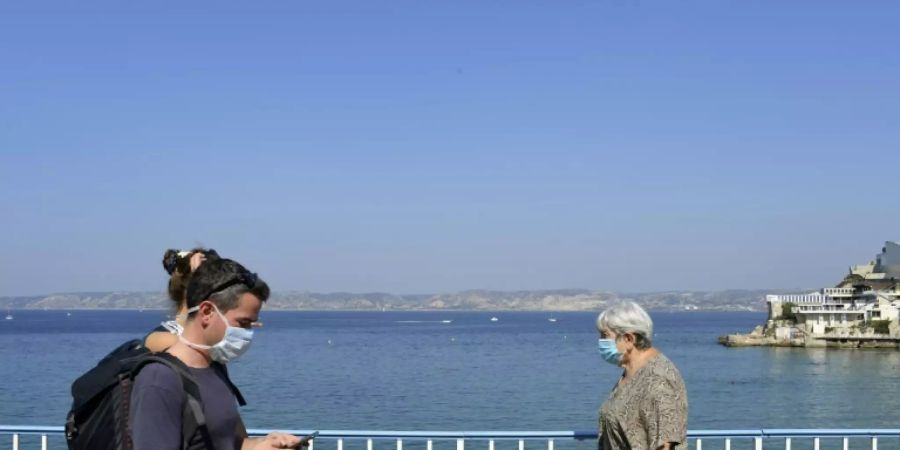 Menschen mit Masken an der Uferpromenade von Marseille