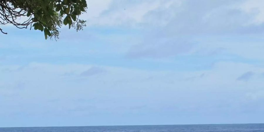 Ein Junge sitzt am Sandstrand auf der Fidschi-Insel Kiribati neben Abfällen. Das Institute for Economics and Peace stellt eine Studie zu ökologischen Bedrohungen und Klimaflüchtlingen vor. Foto: Christiane Oelrich/dpa
