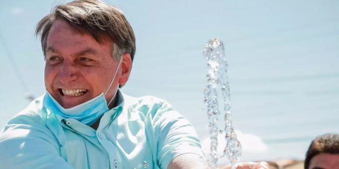HANDOUT - Auf diesem vom brasilianischen Präsidentenamt zur Verfügung gestellten Bild lächelt Jair Bolsonaro, Präsident von Brasilien, mit untergezogenem Mundschutz, während er an einem Brunnen zur lokalen Wasserversorgung mit Wasser spielt. Foto: Alan Santos/Palacio Planalto/dpa jair bolsonaro