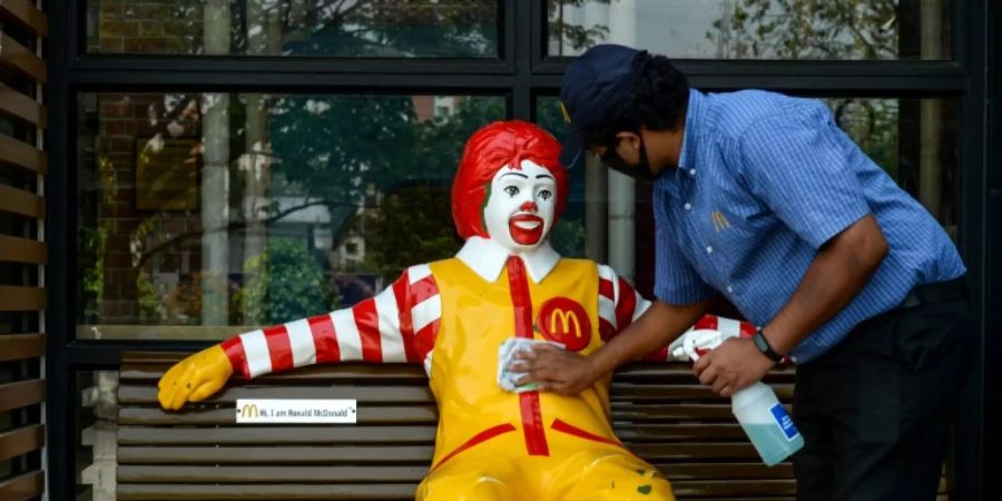 Ein Arbeiter desinfiziert das McDonald's-Maskottchen