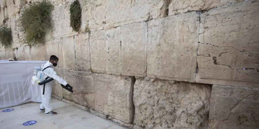 dpatopbilder - Ein Arbeiter verteilt Desinfektionsmittel als Vorsichtsmassnahme gegen das Coronavirus an der Klagemauer, der heiligsten Stätte, an der Juden in Jerusalem beten können. Foto: Sebastian Scheiner/AP/dpa