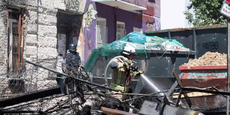 Ein Feuerwehrmann löscht eine brennende Barrikade in der Rigaer Strasse in Berlin-Friedrichshain. Foto: Paul Zinken/dpa-Zentralbild/dpa