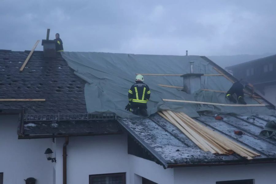 Die Feuerwehr deckt ein beschädigtes Dach ab.