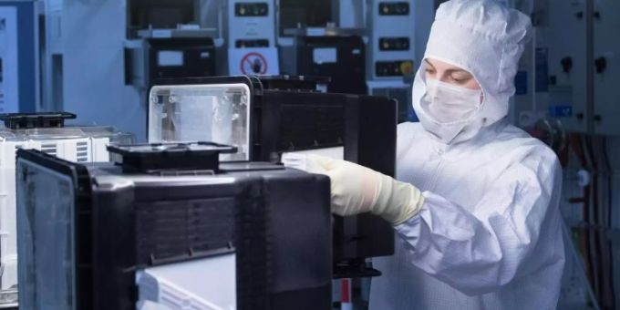 Eine Auszubildende zur Mikrotechnologin trägt in einem Automatisierungslabor des Chiphersteller Globalfoundries (GF) in Dresden ein Kunststoffgehäuse zum Transport von Siliziumwafern. Foto: Sebastian Kahnert/dpa-Zentralbild/dpa Globalfoundries