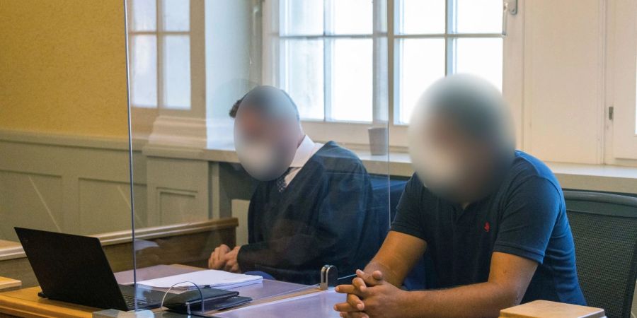 Der Angeklagte (r) sitzt neben seinem Anwalt im Gericht.