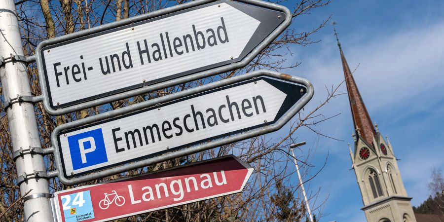 Ein Wegweiser zum Freibad und Hallenbad in Lützelflüh. Rechts der Kirchturm der evangelisch-reformierten Kirche.