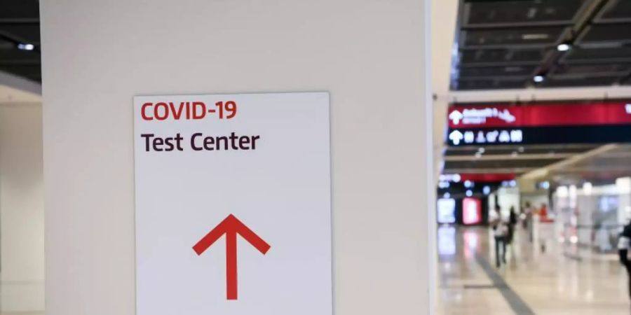 Ein Reisender geht im Flughafen Berlin-Brandenburg (BER) mit einem Koffer nahe eines Hinweisschildes mit der Aufschrift «Covid-19 Test Center». Foto: Jens Kalaene/dpa-Zentralbild/dpa