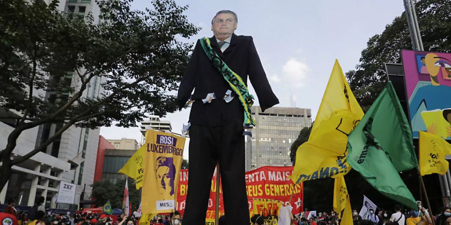 Menschen, die an einem Marsch auf der Avenida Paulista teil, um den Rücktritt des brasilianischen Präsidenten Jair Bolsonaro zu fordern, tragen einen riesigen Ausschnitt von Bolsonaro. Foto: Nelson Antoine/AP/dpa