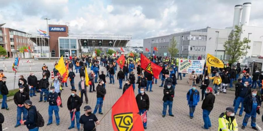 Airbus-Beschäftigte in Hamburg-Finkenwerder demonstrieren im Mai 2021 vor den Toren des Werksgeländes. Die Verhandlungen zwischen Airbus und der IG Metall über den seit Monaten umstrittenen Konzernumbau gehen in die zweite Runde. Foto: Daniel Reinhardt/dpa