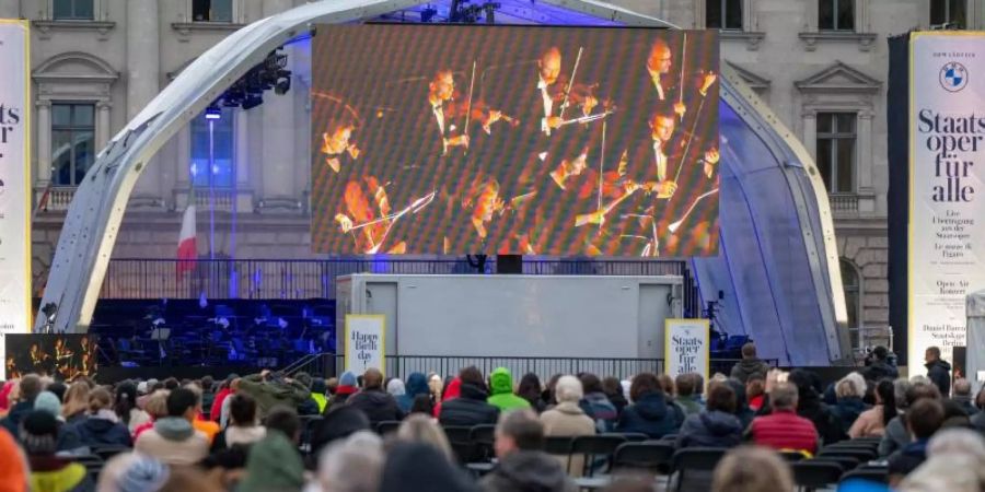 Zahlreiche Zuschauer verfolgen auf dem Bebelplatz die Live-Opernübertragung von Mozarts «Le nozze di Figaro». Foto: Monika Skolimowska/dpa-Zentralbild/dpa