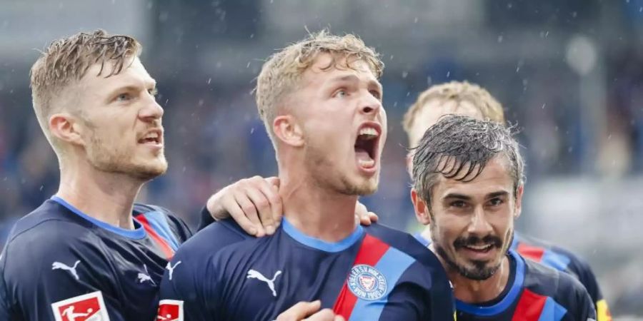 Kiels Alexander Mühling (l-r), Jann-Fiete Arp und Fin Bartels bejubeln Arps Tor zum 2:0. Foto: Frank Molter/dpa