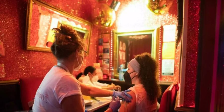 Eine junge Frau lässt sich in einer Bar nahe der Reeperbahn im Hamburger Stadtteil St. Pauli gegen das Coronavirus impfen. Foto: Daniel Reinhardt/dpa