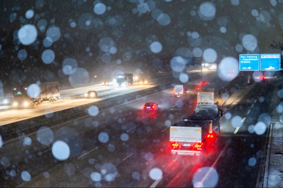 Autos und Lastwagen fahren bei Schneefall auf der Autobahn A5 nahe Zeppelinheim.