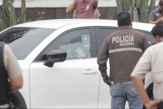 Polizisten untersuchen das von Schusslöchern durchsiebte Auto des Staatsanwalts. Ecuador
