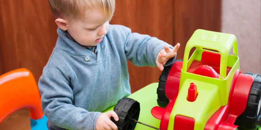 Kind spielt mit Spielzeugtraktor