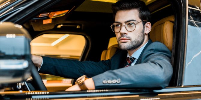 Geschäftsmann mit Brille sitzt im Luxusauto