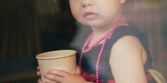 Für kleine Kinder wird empfohlen gänzlich auf den Koffein-Konsum zu verzichten, bei 12- bis 18-Jährigen sollten es nicht mehr als 100 Milligramm täglich sein. kleines mädchen mit kaffeebecher