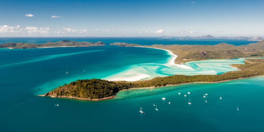 Inselaufnahme von oben, mit blauem Wasser und weiten Sandbänken.