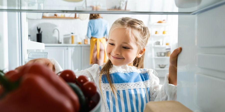 Lächelndes Mädchen schaut in Kühlrschrank