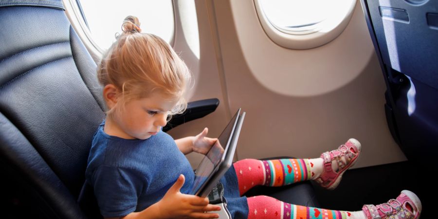 Mädchen im Flugzeug mit Tablet.