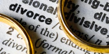 zwei eheringe liegen auf eintrag im dictionary über divorce/ scheidung
