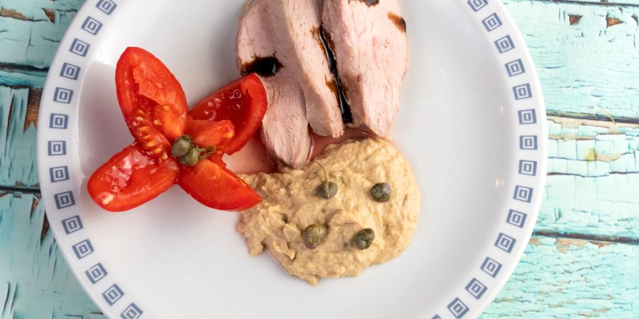 Teller mit Tomaten, Fleisch und Kapern.