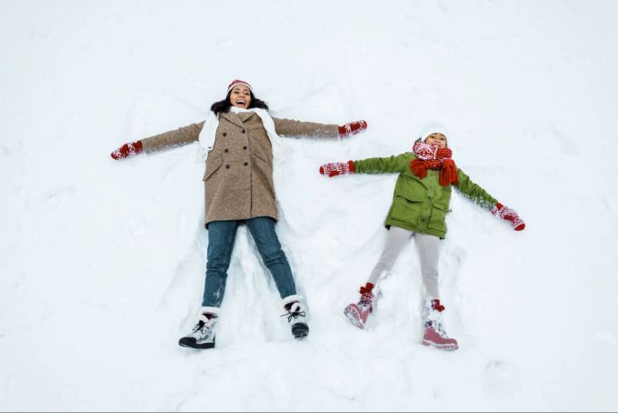 Aus dem «Schneeengel» kann man auch eine weihnachtliche Yogaübung abwandeln. Frau, Kind, Schneeengel