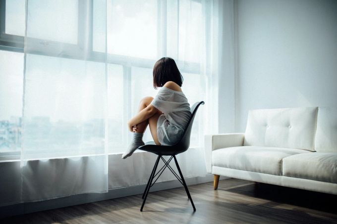 Oft denken wir zu oft über Dinge nach, die nicht mehr veränderbar sind. Frau sitzt vor Fenster