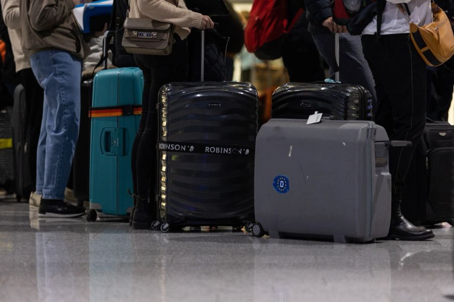 Passagiere mit Koffern warten am Check-in-Schalter am Frankfurter Flughafen.