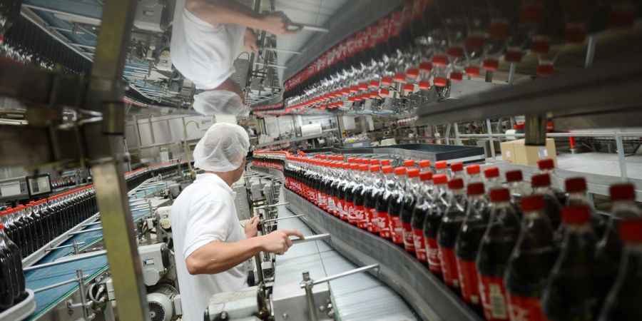 Ein Mitarbeiter steht an einem Transportband mit Getränkeflaschen an den Abfüllanlagen der Coca-Cola Erfrischungsgetränke AG.