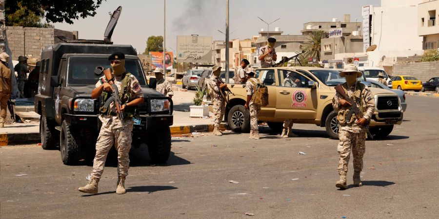 Vermummte Soldaten der libyschen Armee neben Militärfahrzeugen auf einer Strasse in Tripolis.