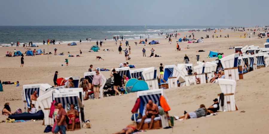 Besucher der Insel Sylt liegen in der strahlenden Sonne am Strand.