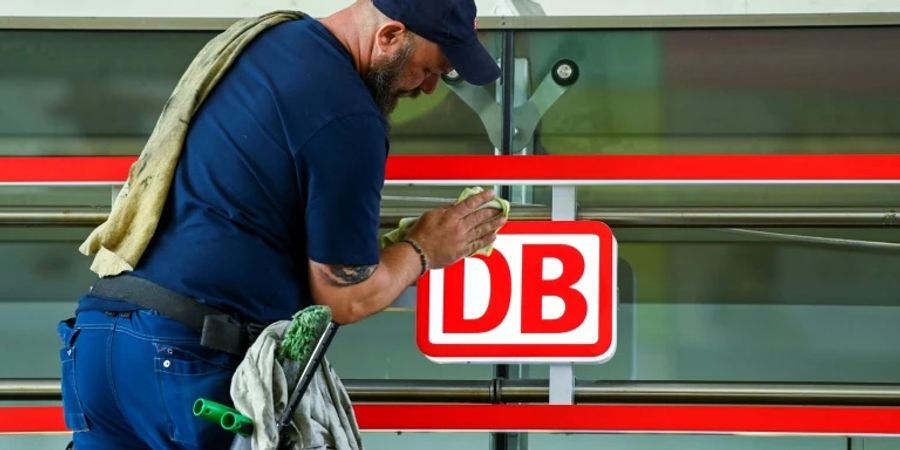 Ein DB-Mitarbeiter putzt ein Schild in Dortmund