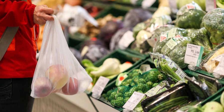 Eine Kundin steht in der Obst- und Gemüseabteilung eines Supermarkts.