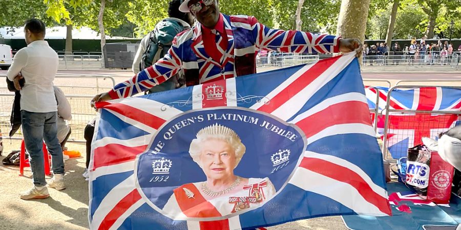 Joseph Afrane schwenkt eine Fahne mit einem Bild der Queen entlang der Pall Mall im Zentrum der Hauptstadt. Foto: Sophie Wingate/PA Wire/dpa