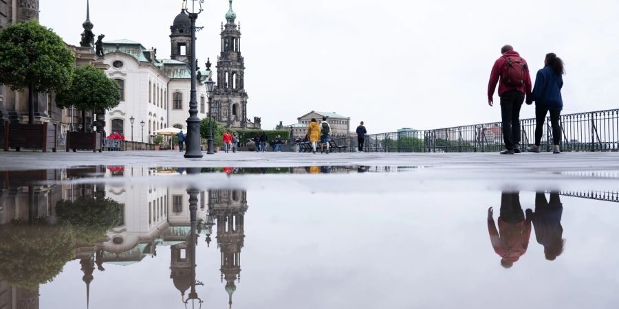 Das Ständehaus (l-r), die Katholische Hofkirche und die Semperoper spiegeln sich in einer Regenpfütze.