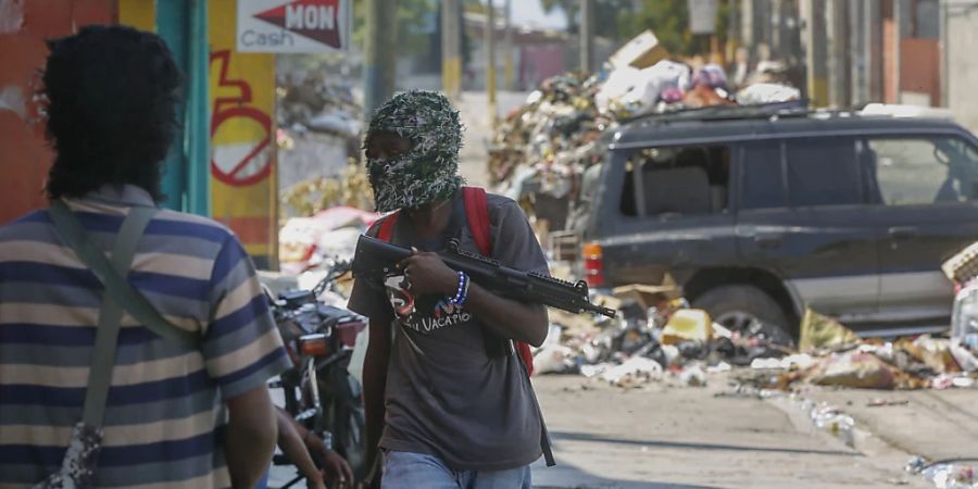 Bewaffnete Mitglieder der Bande G9 and Family stehen an ihrer Strassensperre im Viertel Delmas 6 in Port-au-Prince, Haiti. Mächtige Banden wollen die Interimsregierung in Haiti stürzen. Ihre Gewalt hindert den Regierungschef an der Rückkehr. Der deutsche Botschafter und andere Diplomaten haben das Krisenland verlassen. Foto: Odelyn Joseph/AP/dpa