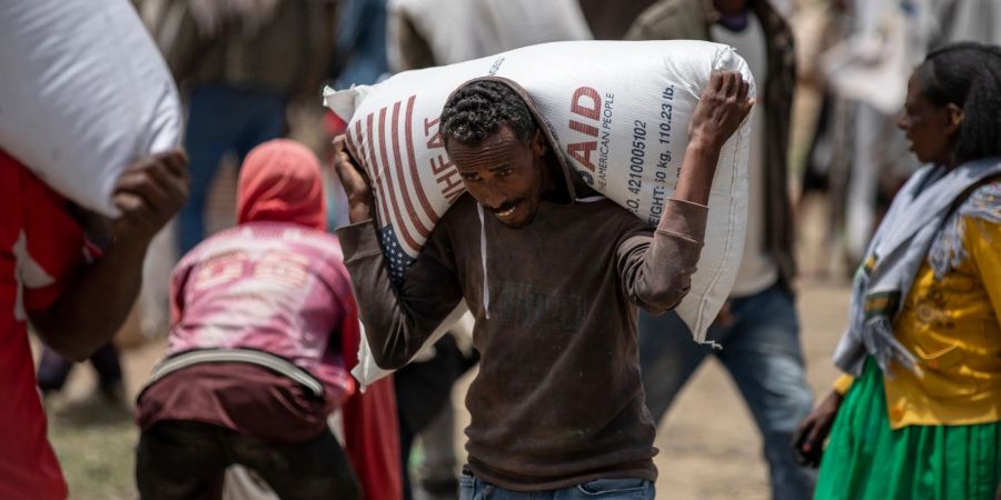 Ein Mann trägt einen Sack Weizen auf den Schultern, der von der Relief Society of Tigray verteilt werden soll.