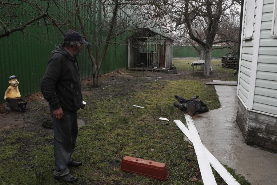 Ein Ukrainer schaut in seinem Garten in Butscha auf einen gefallenen russischen Soldaten.